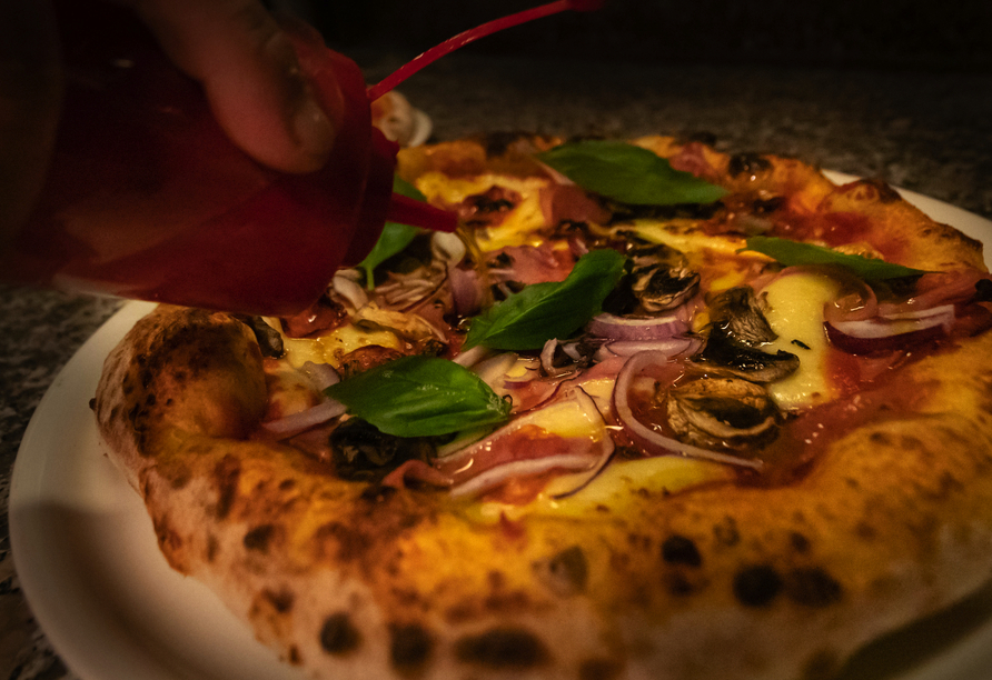 Lassen Sie sich die Pizza in der Pizzeria Trattoria des JUFA Alpenhotels Saalbach schmecken.