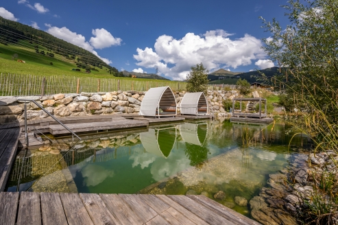 Genießen Sie eine erfrischende Auszeit im Naturbadeteich des Hotels und lassen Sie sich von der traumhaften Panoramasicht verzaubern.