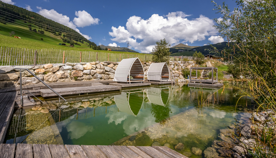 Genießen Sie eine erfrischende Auszeit im Naturbadeteich des Hotels und lassen Sie sich von der traumhaften Panoramasicht verzaubern.